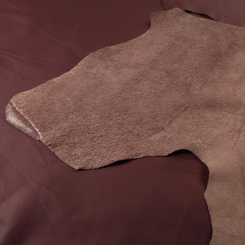 Close-up of Full-grain upholstery leather remnants in maroon colour